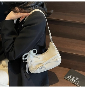 Detail of cream croissant bag with pearl bow pendant and lace trim on stairs