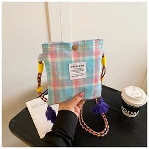 Close-up of retro plaid crossbody bag with tassel and colorful braided rope strap