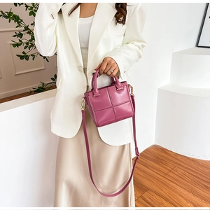 Détail du sac seau bandoulière violet à motifs croisés porté par un mannequin
