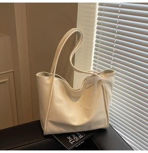 Detailed view of cream leather tote bag featuring a decorative white lace bow accent
