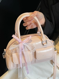Pink leather Boston bag with side bow detail and adjustable shoulder strap shown at 45 degrees