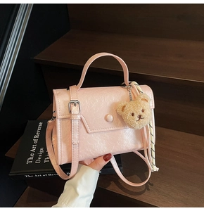 Detail of pink pearlescent leather handbag with bear charm and twill silk scarf detail