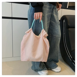 Détail du sac cabas en seersucker rose avec anses à carreaux bleus et texture douce