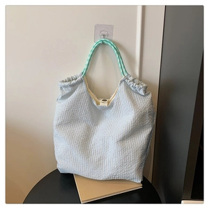 Gros plan sur le sac cabas en seersucker bleu clair avec poignées tissées à rayures vertes