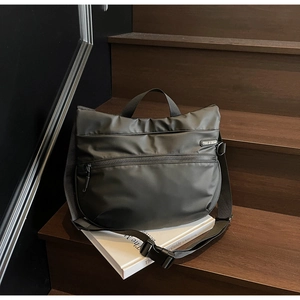 Detail of black sports tote bag with shoulder strap on wooden stairs over a book