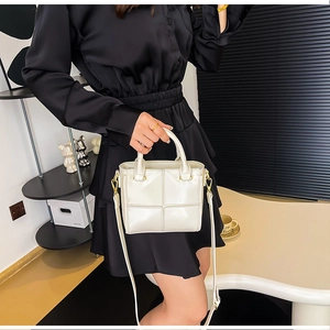 Détail du sac bandoulière blanc brillant avec garnitures dorées et poignée ronde