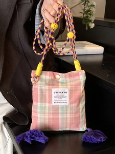 Pink and green plaid canvas crossbody bag with thick woven strap and purple tassels