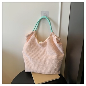 Détail du sac cabas rose gaufré avec des poignées tressées vertes et blanches