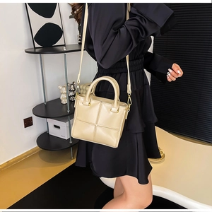 Gros plan du sac seau beige avec bandoulière réglable et détails métalliques dorés