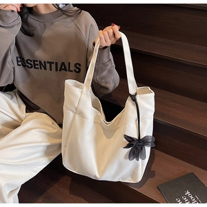 Close-up of white canvas tote bag with black gauze flower pendant on wooden steps