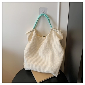 Détail du sac cabas blanc plissé avec poignées à carreaux verts et texture en tissu
