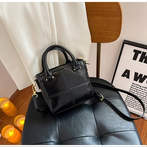 Détail du sac boîte noir brillant avec ferrures dorées et surpiqûres croisées chic