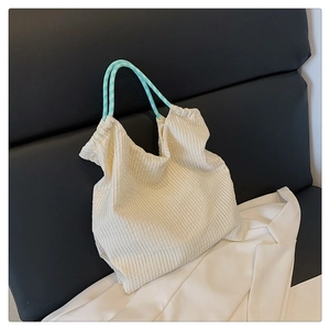 Gros plan d'un sac cabas plissé blanc cassé avec poignées tressées à carreaux bleus