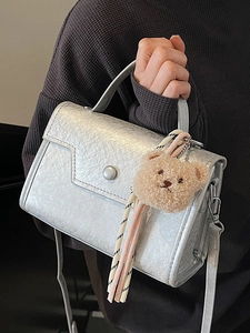 Metallic silver crossbody handbag with textured finish and cute plush bear charm