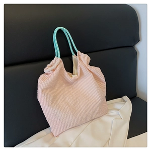 Gros plan du sac cabas plissé rose avec des poignées en corde à carreaux bleus