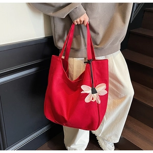 Detail of red canvas tote bag with creative white mesh flower charm accessory
