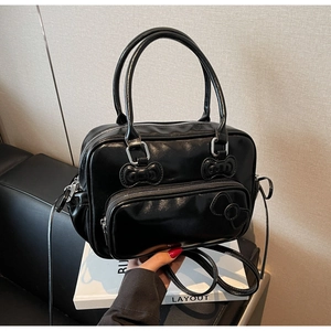 Close-up of black glossy Boston bag featuring decorative bow relief and dual handles