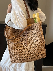 Large straw woven tote bag with brown leather straps and zip closure for beach vacation