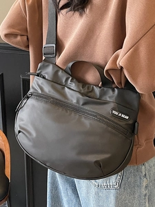 Minimalist black half-moon travel tote bag with adjustable strap and front zipper pocket