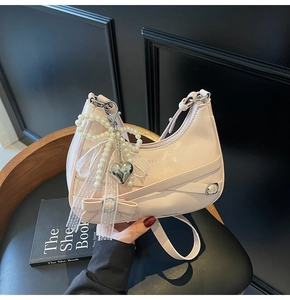 Detail of light pink hobo bag with lace bows, pearl accents and silver heart charm