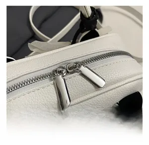 Close-up of polished silver metal zipper and white grainy leather detail on the handbag