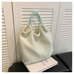 Détail du sac plissé vert clair avec des poignées à pois et une fermeture à pression