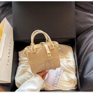 Détail d'un sac seau beige avec surpiqûres quadrillées dans un coffret cadeau en soie