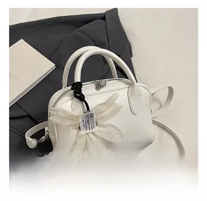 Detail shot of white litchi grain Boston bag featuring a mesh flower charm and silver zipper