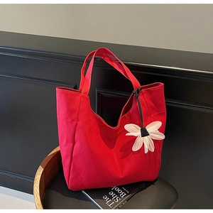 Detail of red canvas tote bag with a white daisy flower charm for daily commuting