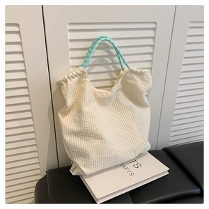 Détail d'un sac cabas en seersucker avec poignée rayée vert menthe et texture plissée