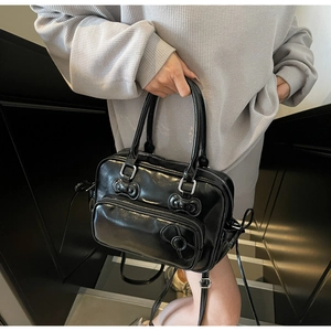 Detail of black glossy bow Boston bag with polished finish and detachable strap