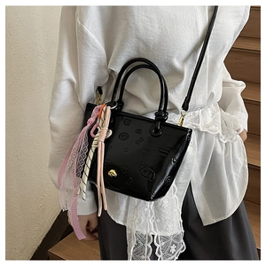 Détail du sac seau noir gaufré avec motifs de chiens et breloque en ruban coloré