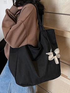 Minimalist black canvas tote bag with white bow accent for women, casual commuter style