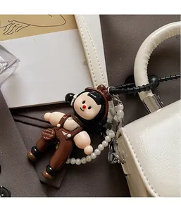 Detail of creative cartoon doll pendant with pearl chain on white luxury handbag