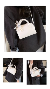 Close-up of white lychee grain leather handbag with decorative tulle flower charm