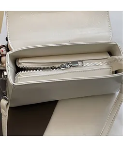 Detailed top view of the cream leather handbag showing a smooth silver metal zipper