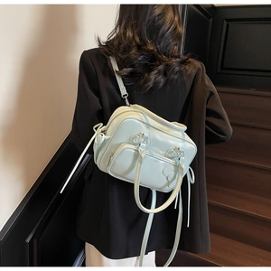 Detail of mint green bow Boston bag in glossy leather shown on a model during use