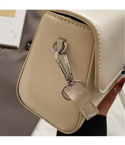 Detailed view of silver metal hooks and accordion side gussets on beige leather bag