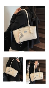 Detail of cream-white tote bag featuring bear embossing and woven rope pendant charm
