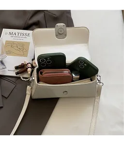 Detail showing high-capacity interior of beige square bag with phone and wallet storage