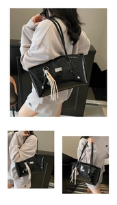 Close-up of black tote bag featuring embossed cartoon bear patterns and a silver logo plate