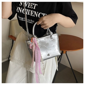 Détail du sac seau miroir argenté avec motifs gaufrés en 3D et breloques colorées