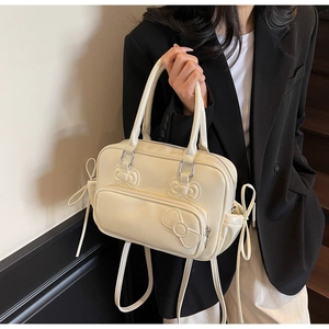Detailed close-up of cream bow-embossed Boston bag with versatile multi-way straps
