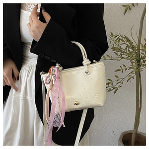 Détail du sac seau blanc crème avec motif de chien en relief et ruban de dentelle chic