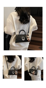 Detail of elegant black glossy leather bag featuring silver oval lock and pearl charm