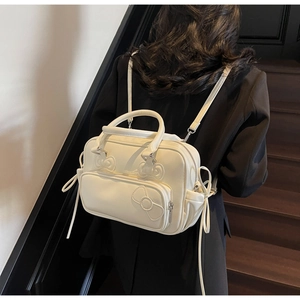 Detail of cream white multi-way bow backpack shown on a model against a minimalist background