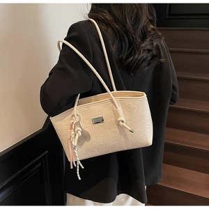 Close-up of creamy beige shoulder bag with embossed cartoon bear and rabbit patterns