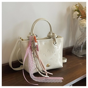 Gros plan du sac seau en cuir PU crème avec motifs en relief et accessoires de décoration