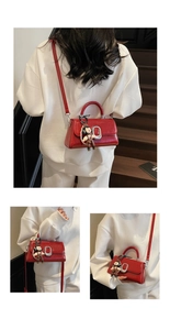Detail of red glossy patent leather square bag with silver buckle and cartoon charm