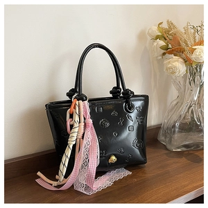 Détail d'un sac seau en cuir verni noir avec motifs de dessins animés en relief et charms